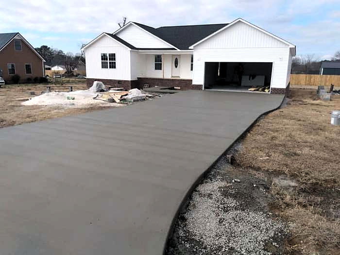 New concrete driveway leading to a home's attached garage