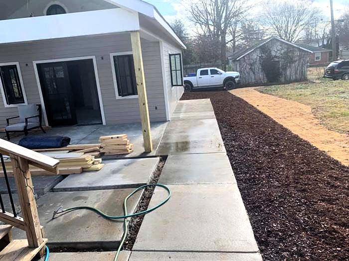 Concrete walkway running alongside a home and landscaped bed