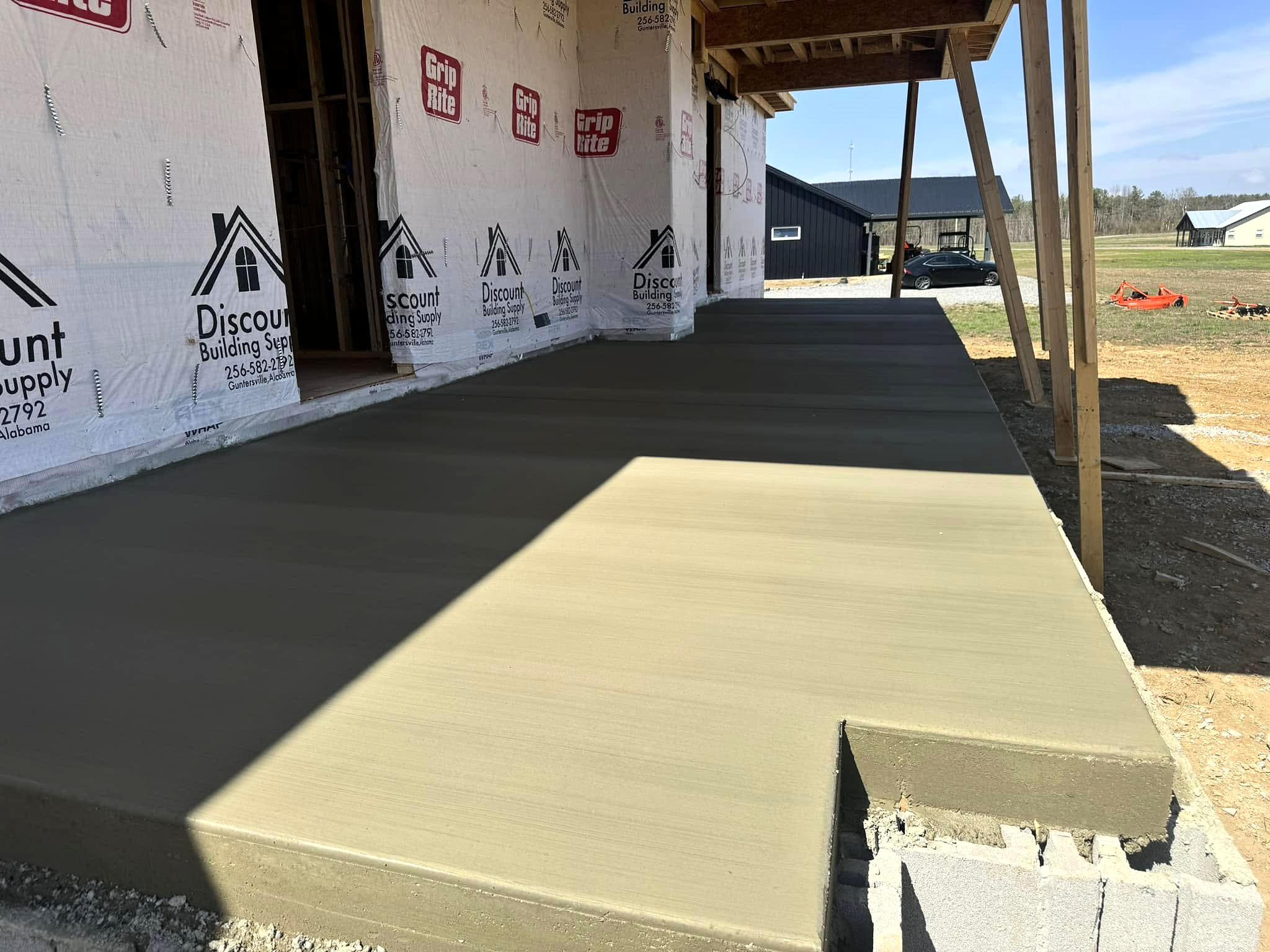 New concrete porch slab beneath the roof of a home under construction