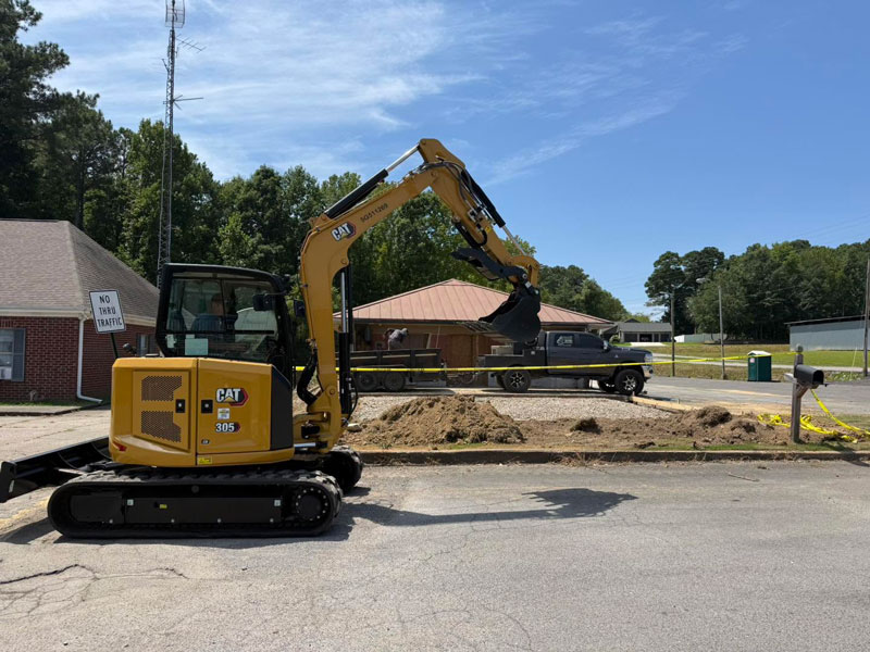 Tracked excavator loading excavated material into a dump trailer at a residential jobsite